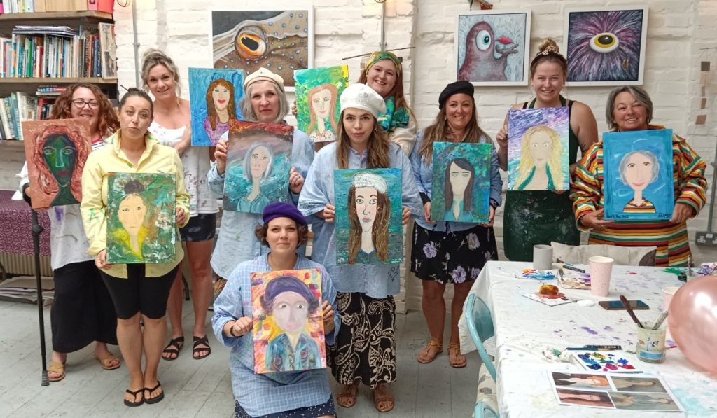 Image of a hen party group holding their finished portraits painted by each other